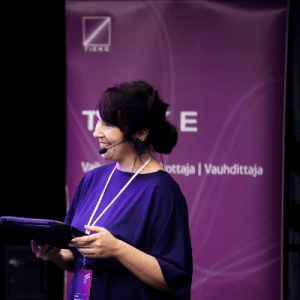 Tummahiuksinen nainen katsoo sivulle kädessään musta tabletti.