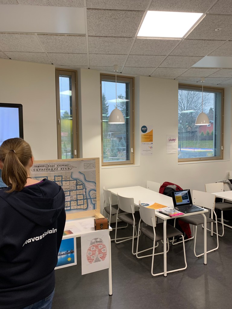 Pieni osa luokkahuonetta. Vasemmalla nainen selkä kameraan Tavastian huppari päällä.