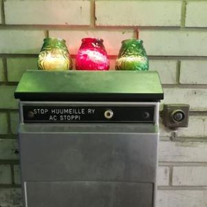 Postilaatikko seinässä. Laatikon päällä kolme kynttilää.